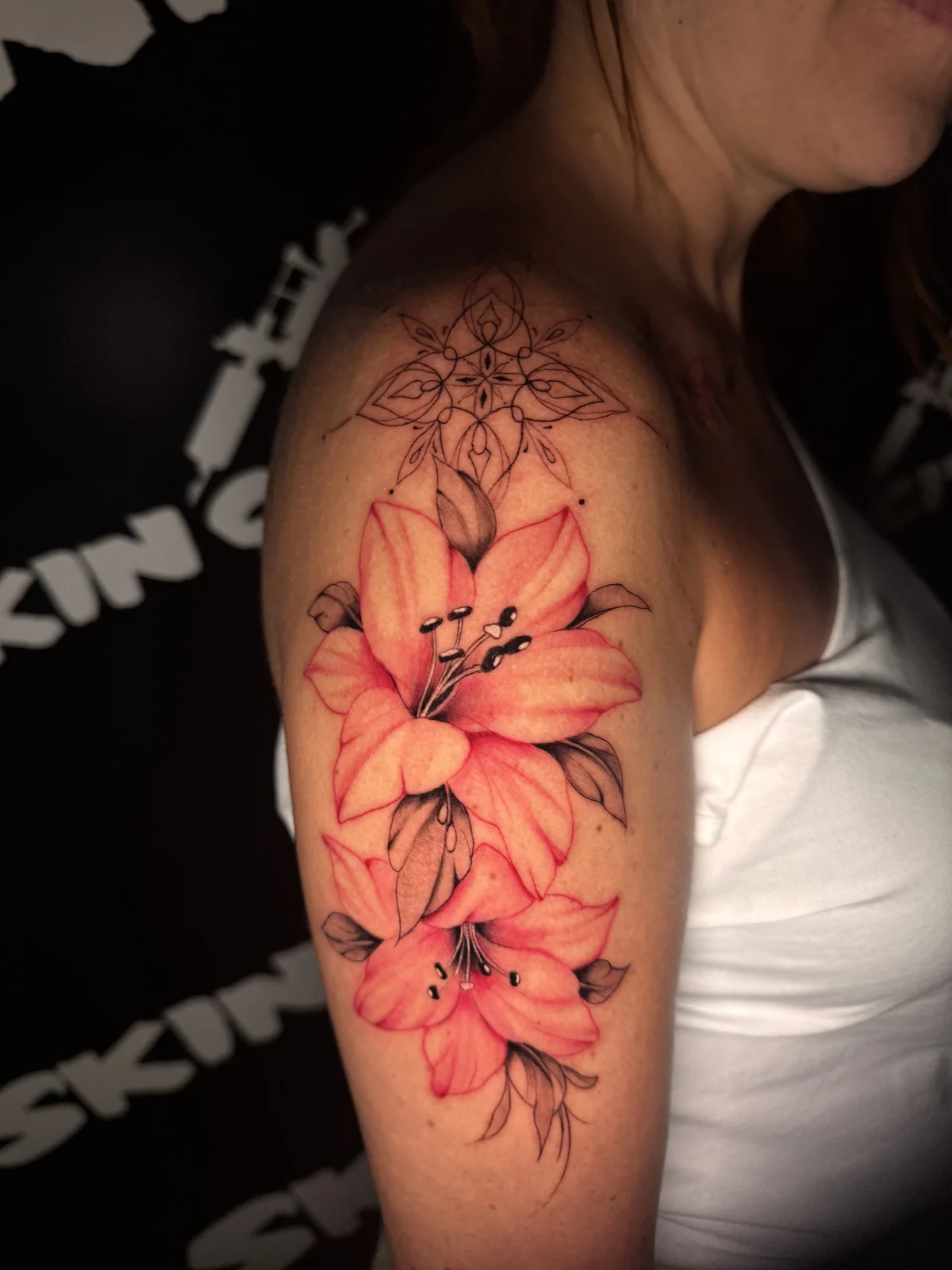 Farbiges Blumen-Tattoo mit rosafarbenen Blüten und dunklen Blättern am Unterarm – Arbeit von Merci, Skin City Tattoo.