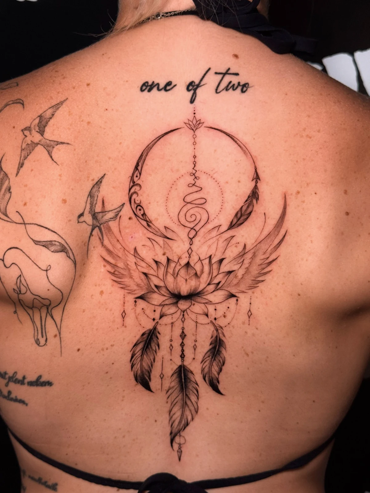 Großes Rücken-Tattoo mit Lotusblüte, Federn und kreisförmigen Fineline-Ornamenten – tätowiert von Merci bei Skin City Tattoo.