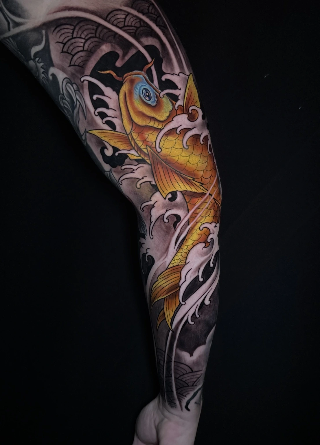 Goldener Koi in stilisierten Wellen als japanisch inspiriertes Beintattoo